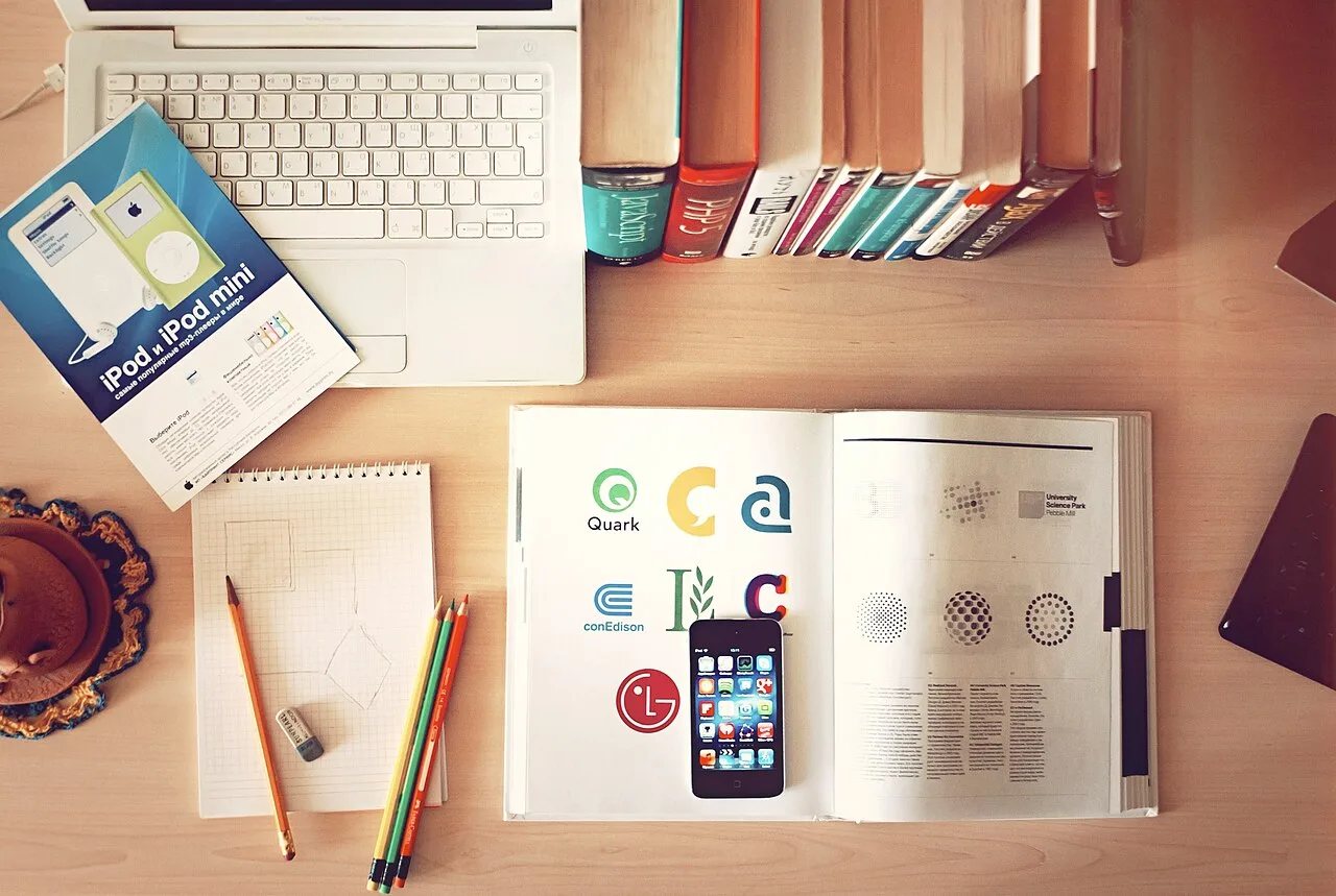 Books, notebooks, pencils, and a laptop arranged across a desk