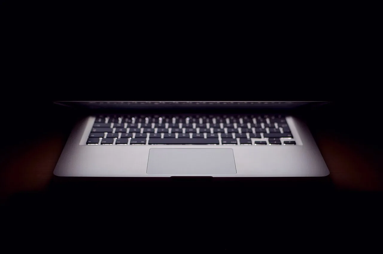 A partly closed laptop in a dark room