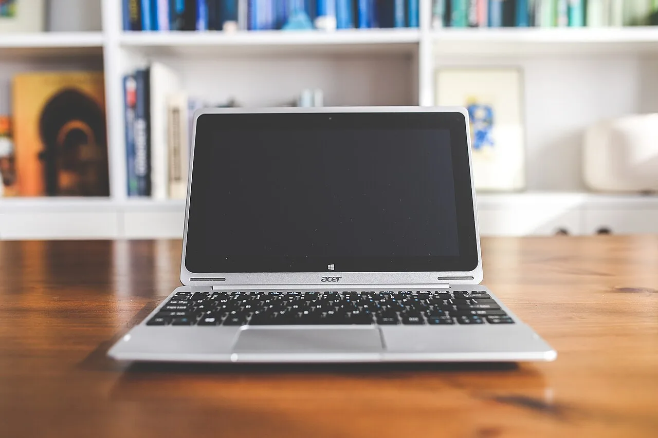 An open laptop on a wooden table in a bright room