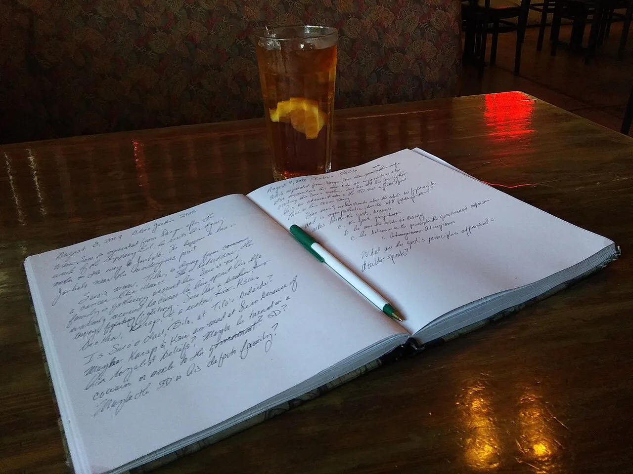 An open handwritten notebook and pen on a wooden table