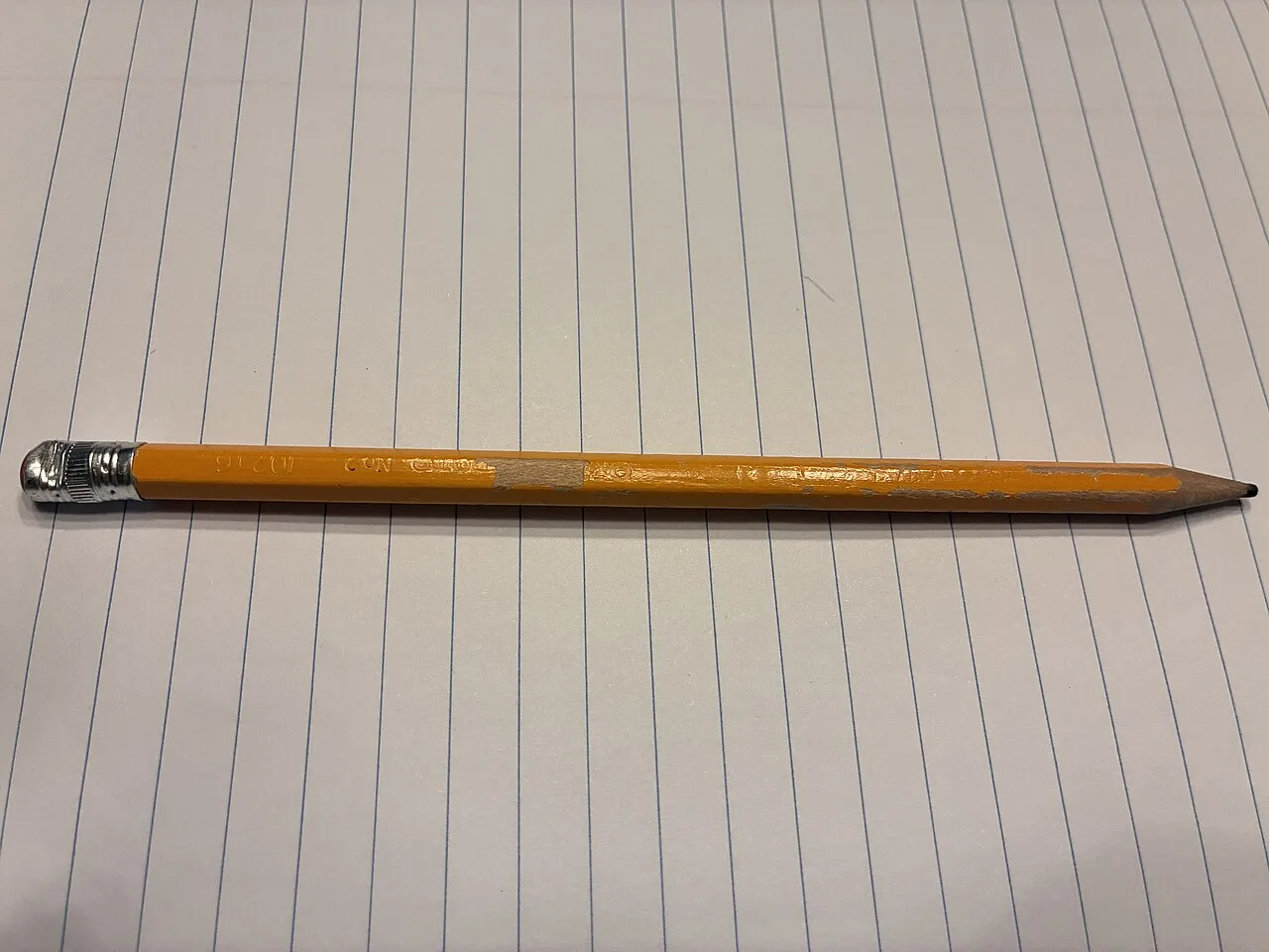 A yellow pencil lying across a lined notebook