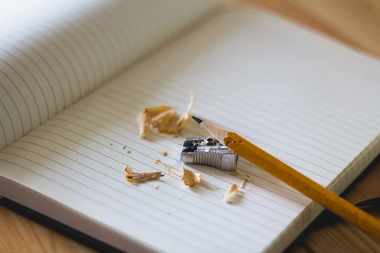 A sharpened pencil and pencil shavings on an open notebook