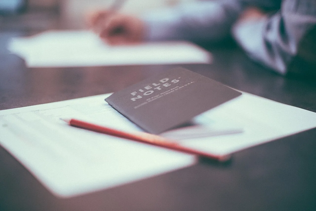 A small closed notebook and pencil resting on a desk