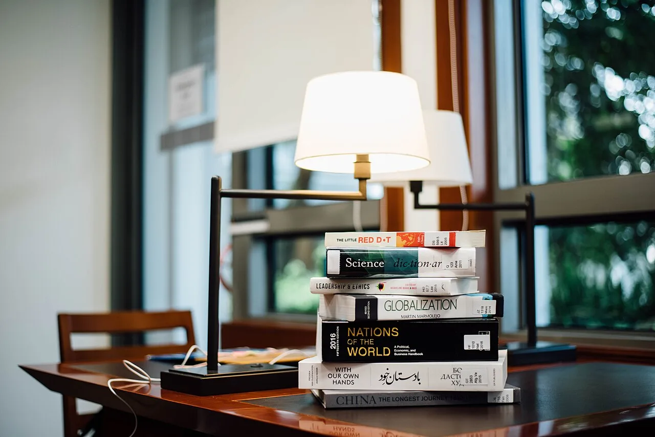 Books and a reading lamp beside a window