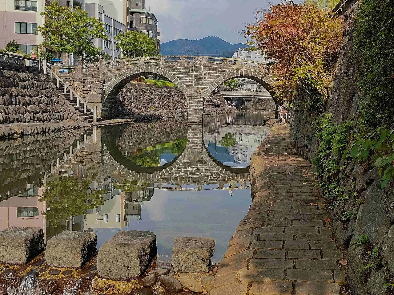 Stepping stones leading toward a stone bridge over a river
