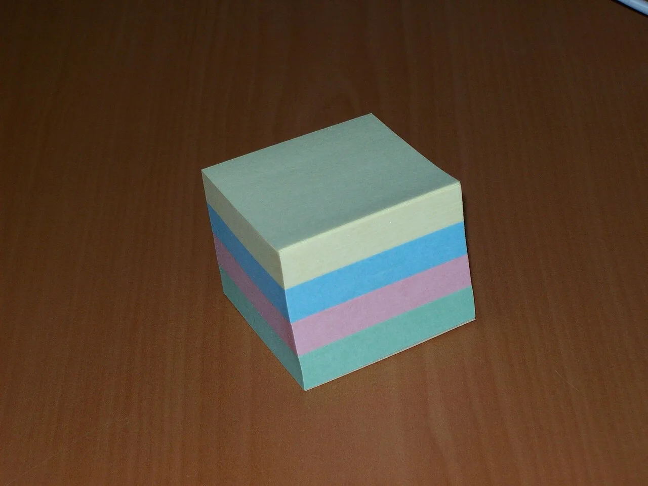 A neatly stacked block of colored sticky notes