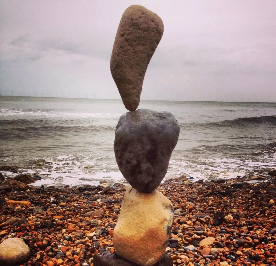 Three stones balanced above a pebbled shoreline