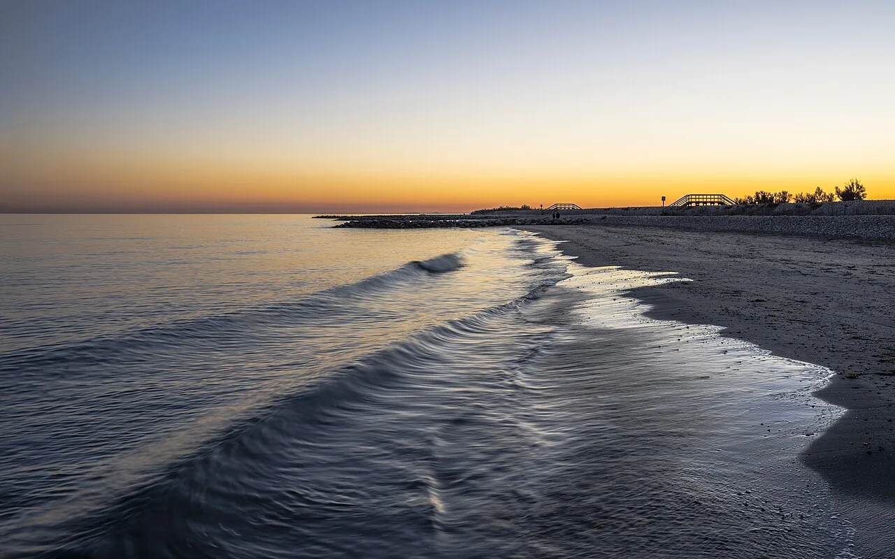 Gentle waves reaching a beach as the sun sets