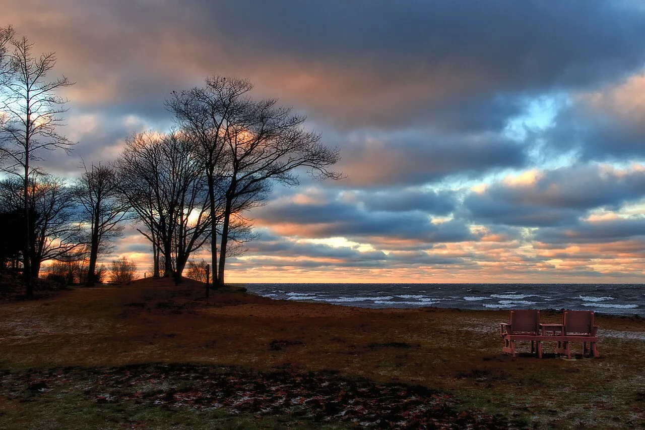 Two chairs beside a lake beneath a dramatic evening sky