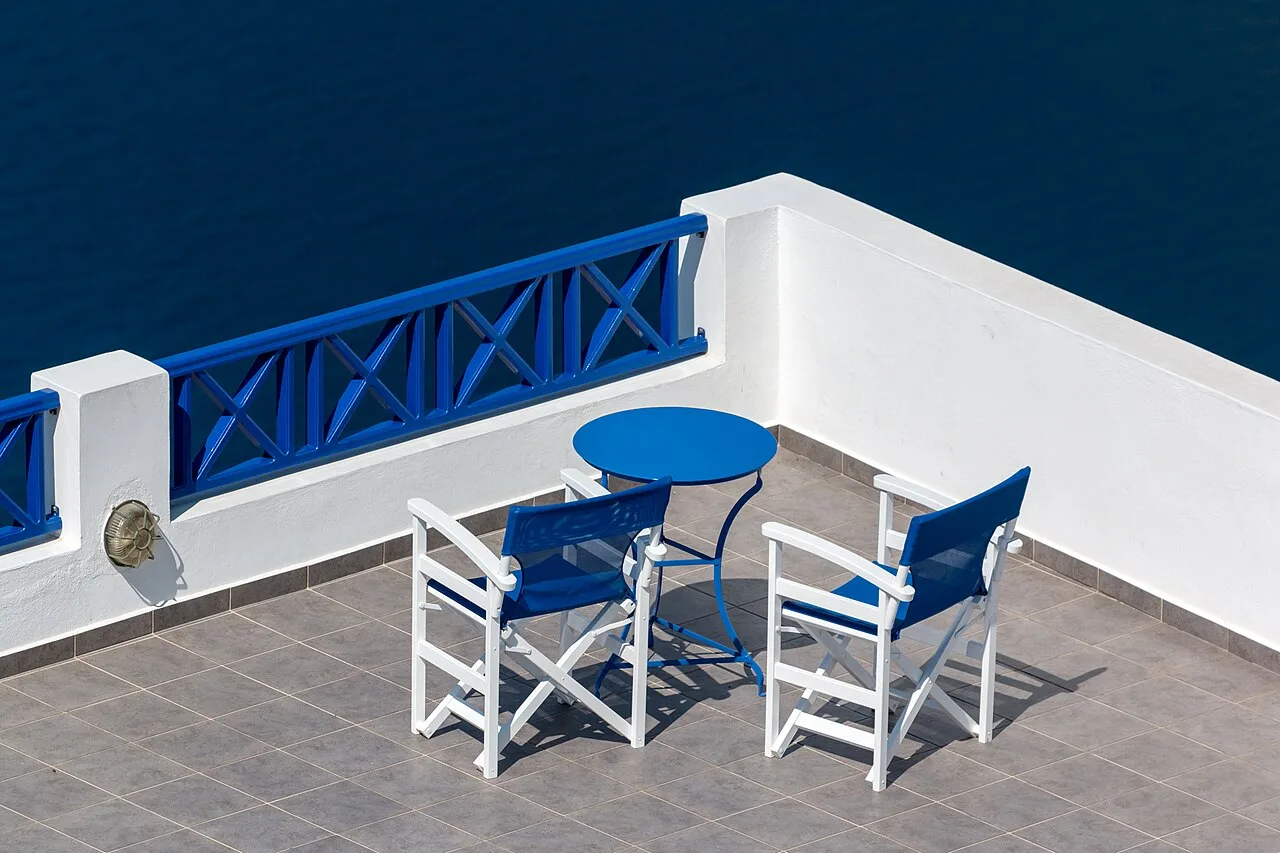 Two chairs and a small table on a terrace overlooking the sea